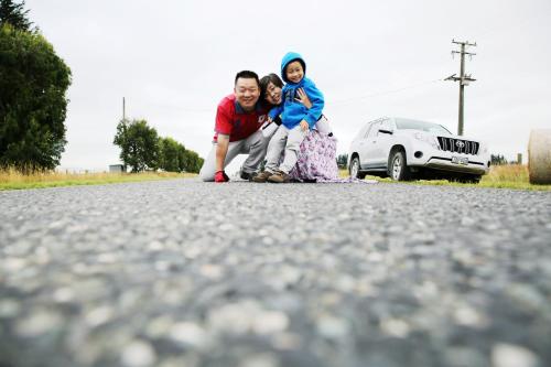 a family sitting on the side of a road with a car at Kepler Oaks Chalet in Te Anau