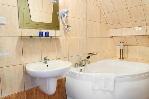 een badkamer met een wastafel en een ligbad bij Motel Arkadia in Koszalin