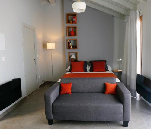 - une chambre avec un lit et un canapé avec des oreillers orange dans l'établissement Galpon Boutique Aldea De Abaixo, à Palas de Rei