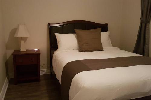 a bedroom with a bed and a night stand with a lamp at 2-Bedroom Apartment Sweet #5 by Amazing Property Rentals in Gatineau