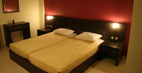 a bedroom with a large bed with a red wall at Studios Karavos in Aliveri