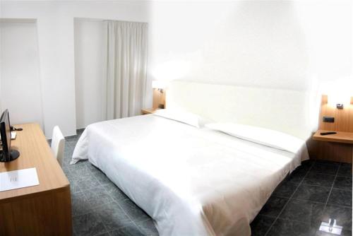 a bedroom with a large white bed and a desk at Vea Resort Hotel in Mercato San Severino