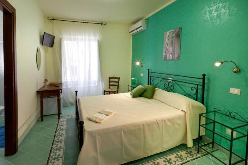a bedroom with a bed and a green wall at Le 5 Torri in Trapani