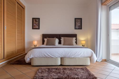 - une chambre dotée d'un grand lit avec des draps et des oreillers blancs dans l'établissement Maravilhoso T2 Vila da Praia, à Amoreira