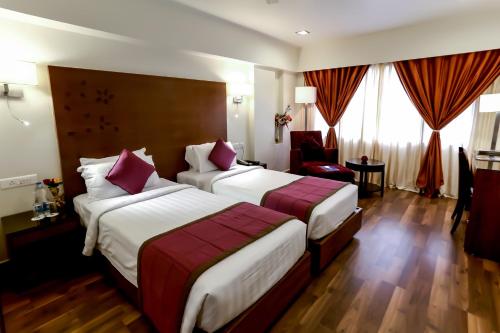 a hotel room with two beds and a chair at Best Western Ramachandra in Visakhapatnam