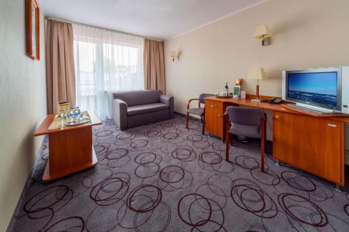 a hotel room with a desk and a television at Hotel Lidia Spa & Wellness in Darłówko