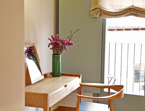 a vase of flowers on a wooden table with a mirror at Hotel Ayllon in Ayllón