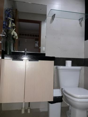 a bathroom with a white toilet and a sink at Mar do Cabo Branco Residence in João Pessoa