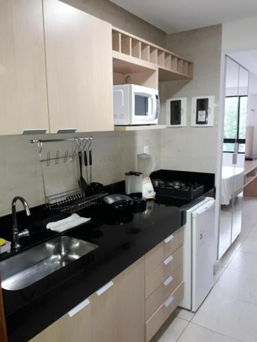 a kitchen with a sink and a microwave at Mar do Cabo Branco Residence in João Pessoa