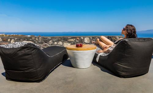 a man sitting on a couch with a cup of coffee at Elysian Santorini in Oia
