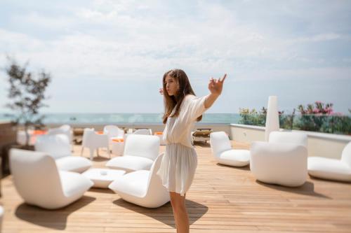 a woman in a white dress standing in a room with chairs at Hotel Ambassador in Bibione