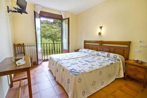 a bedroom with a bed and a table and a window at Hospedería El Cantio in Oreña