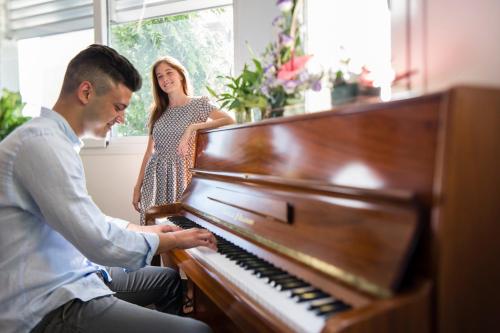 a man playing a piano with a woman standing behind him at Hotel Ambassador in Bibione