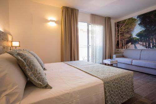 a bedroom with a bed with a couch and a window at Hotel Ambassador in Bibione