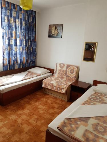 a room with two beds and a chair and a window at Guest Rooms Denitsa in Obzor