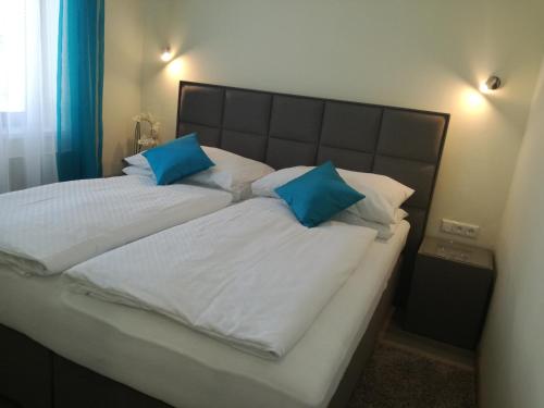 a bed with two blue pillows on top of it at garni Hotel S.O.G.* * * in Trenčín