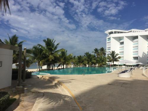 a resort swimming pool with palm trees and a building at Marbella Juan Dolio in Juan Dolio