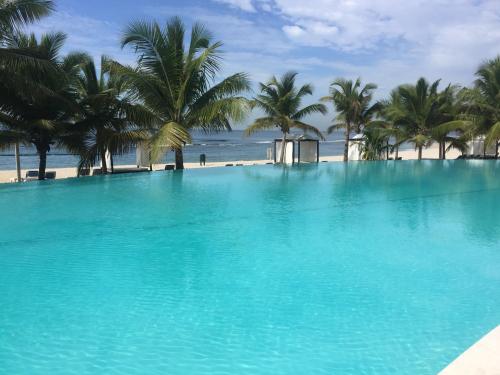 a large swimming pool next to a beach with palm trees at Marbella Juan Dolio in Juan Dolio