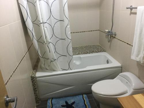 a bathroom with a tub and a toilet and a shower curtain at Marbella Juan Dolio in Juan Dolio