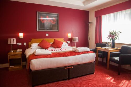 um quarto de hotel com uma cama grande com paredes vermelhas em Adelphi Portrush em Portrush