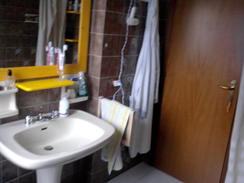 een badkamer met een wastafel, een spiegel en een deur bij Non Solo Breakfast in Imola