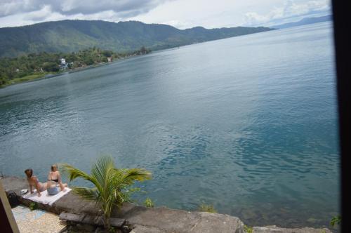 two people sitting on the edge of a body of water at Reggae Guest House in Tuk Tuk