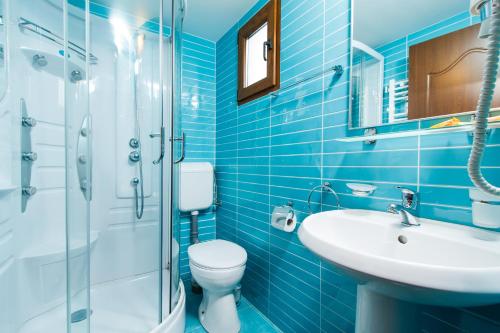 La salle de bains bleue est pourvue de toilettes et d'un lavabo. dans l'établissement Pensiunea Andrei, à Râmnicu Vâlcea