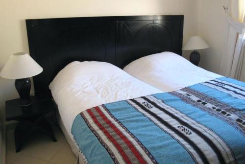 a large bed with a black headboard and two lamps at Auberge Dar Najmat in Mirleft