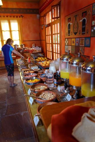 a person standing in front of a buffet line with food at Hotel Pakaritampu in Ollantaytambo