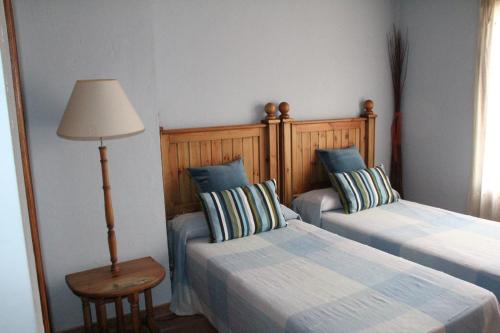 a bedroom with two beds and a lamp and a table at Casa Rural Celtia in Aguilar del Río Alhama