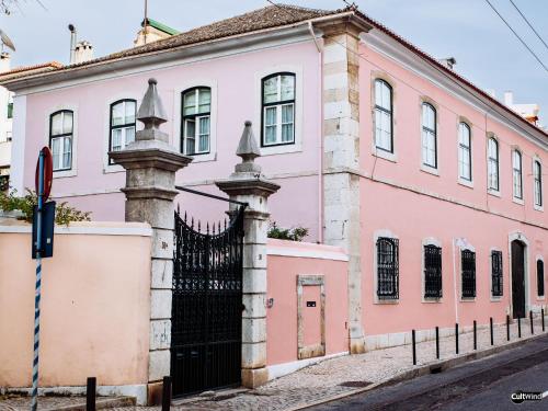 a pink building with a black gate on a street at Villa Marquês near Tejo River in Cruz Quebrada