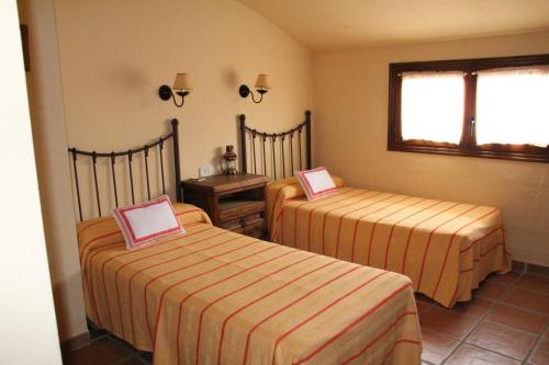 a room with two beds and a table and a window at Casa Rural Celtia in Aguilar del Río Alhama