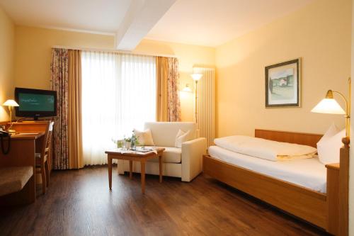 una camera d'albergo con letto, sedia e TV di Hotel & Restaurant Dornweiler Hof a Illertissen