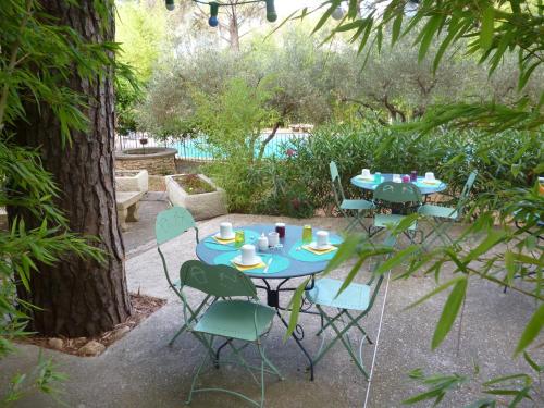 une table et des chaises bleues dans un jardin dans l'établissement La Bastide des Pins, à Castillon-du-Gard