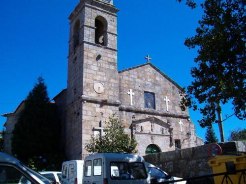 an old stone church with a clock tower in a parking lot at Hotel O Lagar in Cambados