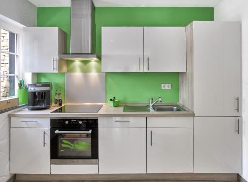 eine weiße Küche mit grünen Wänden und weißen Schränken in der Unterkunft Rhein-Mosel-Ferienhaus in Brodenbach