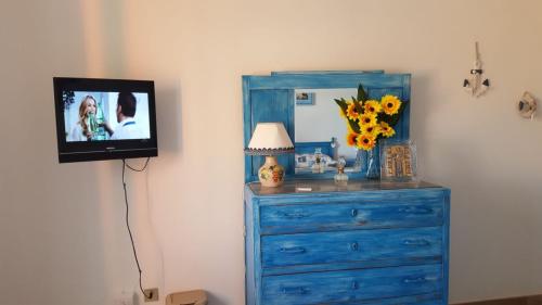 a room with a blue dresser and a tv on a wall at B&B Le Peonie in Badesi