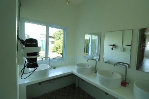 une salle de bain avec trois lavabos et une grande fenêtre dans l'établissement Krit Hostel, à Bangkok