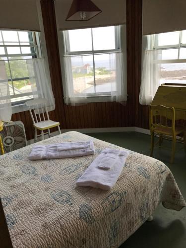 a bedroom with two towels on a bed with windows at The 8th Maine Regiment Lodge and Museum in Peaks Island