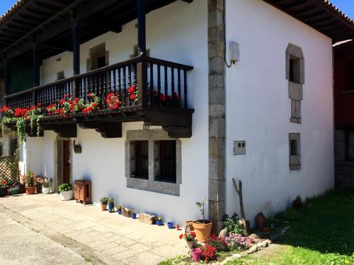 un edificio blanco con un balcón con flores. en A Pie De Picos, en Caño