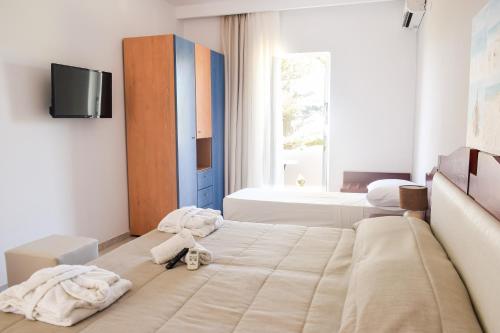 a bedroom with two beds and a tv on the wall at Dias in Georgioupolis