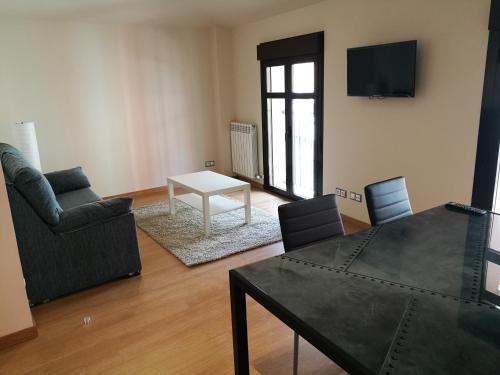 uma sala de estar com uma mesa e cadeiras e uma televisão em Apartamentos Espolón em Logroño