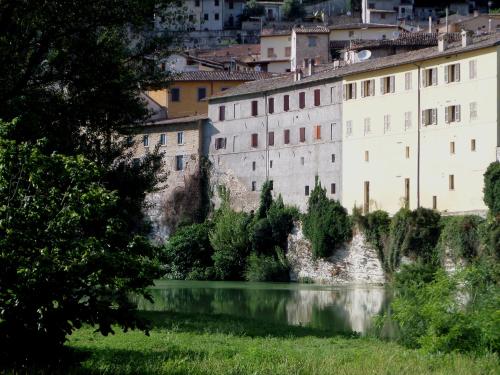 a building next to a river in front of a city at La Finestra sul Fiume in Fossombrone