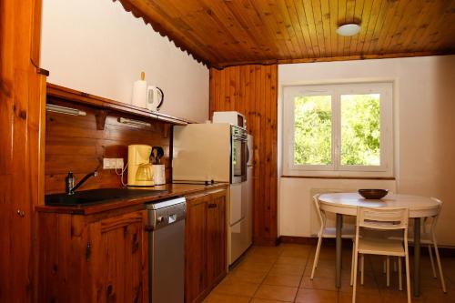 une cuisine avec une table et un réfrigérateur blanc dans l'établissement Gites L'épilobe, à Saint-Léger-les-Mélèzes
