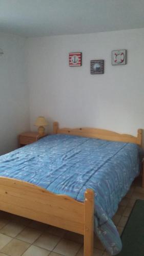 - une chambre avec un lit en bois et une couette bleue dans l'établissement Gîte Anne et Jean, à Pordic