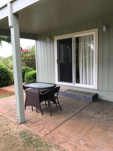 a patio with a table and chairs on a house at Hale Pua Villa - Seaside Studio in Koloa