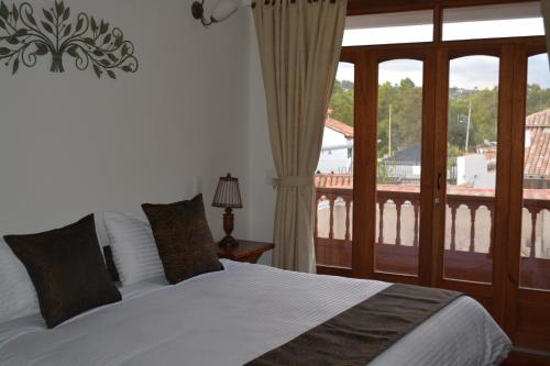 a bedroom with a bed and a large window at Hotel El Giro in Villa de Leyva