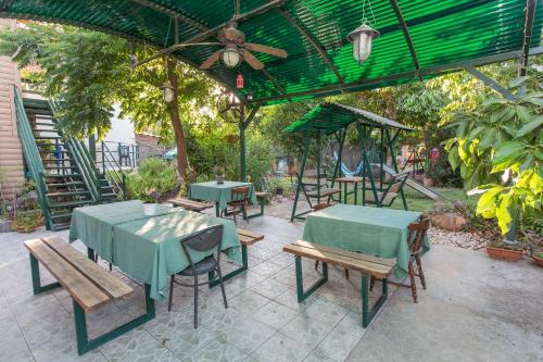 a patio with tables and benches and a green umbrella at Leyad Hashmura Lodging in Yesod Hamaala