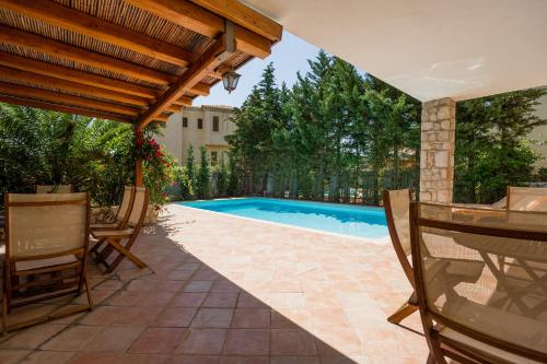 a patio with a pool and a table and chairs at Porto Heli Villa in Porto Heli