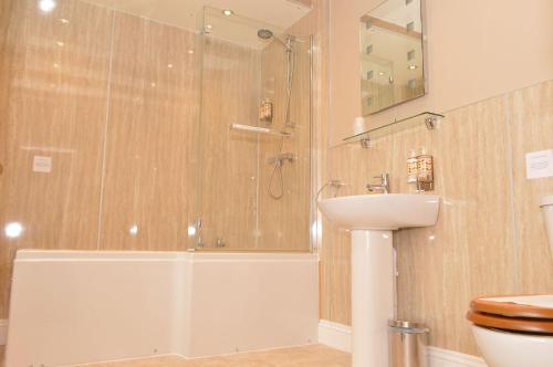 uma casa de banho com um chuveiro, um WC e um lavatório. em Red Lion Inn em Newbrough